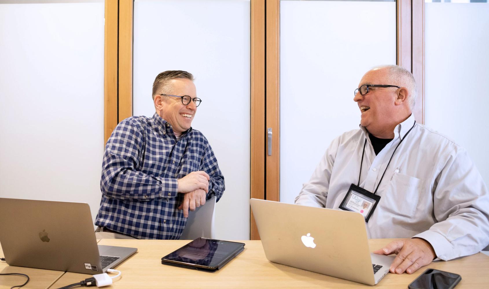 UCSF Student Disability Services (SDS) co-directors Clay Littrell and Timothy Montgomery are sitting at a table with their laptops open.